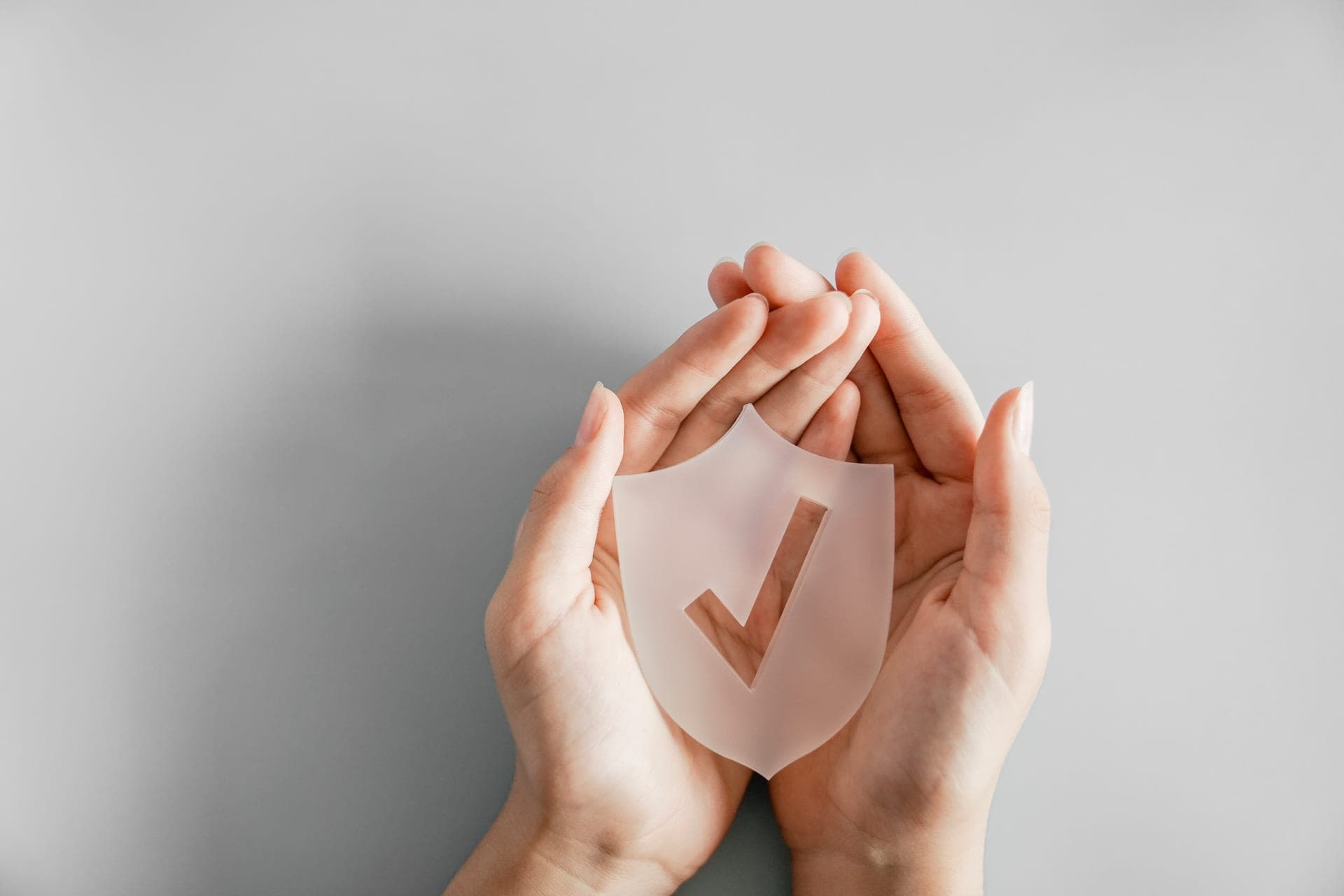 Ръце, държащи щит с отметка – символ на сигурност и доверие